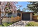 A modern home featuring a detached garage with wood accents and a well-maintained lawn at 1485 S Jasmine Way, Denver, CO 80224