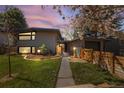 Modern home with wood siding, fresh landscaping, and a walkway leading to the front door at twilight at 1485 S Jasmine Way, Denver, CO 80224