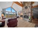 Bright living room with stone fireplace, vaulted ceilings, and mountain views from large windows at 394 S Ponderosa Way, Evergreen, CO 80439