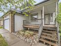 Inviting front porch with wooden stairs, gray railings, and river rock landscaping at 11851 Elm Dr, Thornton, CO 80233