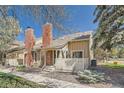 Inviting two-story home showcases a red brick chimney and tan siding with a white picket fence in the front yard at 9957 Grove Way # F, Westminster, CO 80031