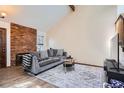 Cozy living room featuring a decorative brick fireplace, a gray sofa, and a vaulted ceiling at 9957 Grove Way # F, Westminster, CO 80031