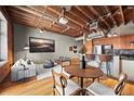 Open-concept living space with exposed wood ceilings, modern furnishings, and abundant natural light at 1800 Lawrence St # 303, Denver, CO 80202