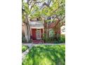 Two-story brick home with front porch shaded by mature trees, offering a cozy and inviting curb appeal at 2410 W 36Th Ave, Denver, CO 80211