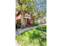 A charming two-story red brick home with a cozy front porch surrounded by mature trees and a green lawn at 2410 W 36Th Ave, Denver, CO 80211