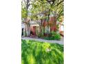 A brick two-story home is beautifully shaded by mature trees, enhancing its curb appeal at 2410 W 36Th Ave, Denver, CO 80211