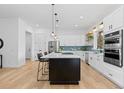 Modern kitchen with white cabinets, a large island, and light wood floors at 8006 S Settlers Dr, Morrison, CO 80465