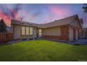 Charming single-Gathering home at twilight featuring a well-manicured lawn and an attached two-car garage at 4548 Gibraltar Way, Denver, CO 80249