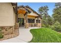 Inviting front porch and entry to this home has stone accents and a manicured lawn at 8280 Bannock Dr, Larkspur, CO 80118
