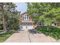 Inviting two-story home with a two-car garage, landscaped front yard, and mature trees at 7445 Shoreham Pl, Castle Pines, CO 80108