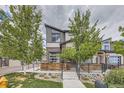 Striking modern home with a unique garage door-style window, complemented by mature trees and professional landscaping at 10117 Morrison Rd, Lakewood, CO 80227