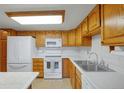 Bright kitchen featuring white appliances, wood cabinets, and a double basin sink at 14001 E Marina Dr # 607, Aurora, CO 80014