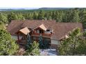Beautiful home with wood features and a brown roof nestled in a mature forest at 7076 Boreas Rd, Larkspur, CO 80118