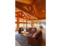 Spacious living room with exposed wood beams, large windows, and comfortable leather furniture at 7076 Boreas Rd, Larkspur, CO 80118