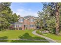 A well-maintained front lawn, trees, and flowers are surrounding this red brick home with blue shutters at 5428 Golden Currant Way, Parker, CO 80134