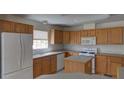 Functional kitchen with wooden cabinets, white appliances, and a center island at 233 Cherokee Ct, Brighton, CO 80603