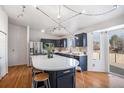 Well-lit kitchen features navy cabinets, stainless steel appliances, a modern lighting fixture, and hardwood floors at 1965 E 127Th Cir, Thornton, CO 80241