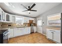 Functional kitchen with white cabinetry, neutral countertops, a ceiling fan and tiled flooring at 6690 Albion St, Commerce City, CO 80022