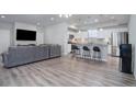 Open-concept living room featuring a gray sofa, wood floors, and a view of the kitchen with a large island at 28418 E 8Th Pl, Watkins, CO 80137