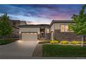 Charming single-Gathering home with stone accents, a manicured lawn, and a two-car garage at dusk at 14303 Glenayre Cir, Parker, CO 80134