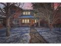Charming two-story brick home with a snow-covered front yard and a welcoming pathway under a sunset sky at 2038 S Columbine St, Denver, CO 80210