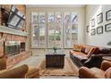 Cozy living room featuring a brick fireplace, large windows, hardwood floors, and comfortable leather seating at 6213 S Lima Way, Englewood, CO 80111
