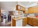 Functional kitchen with wooden cabinets, white appliances, and an open view to the living area at 11923 E Ford Dr, Aurora, CO 80012