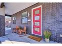 Welcoming front porch featuring rocking chairs, sleek brickwork, and a vibrant red door at 2122 S Ogden St, Denver, CO 80210