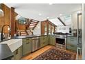 Bright kitchen with stainless steel appliances, a farmhouse sink, and a view of the wooden staircase at 7221 S Brook Forest Rd, Evergreen, CO 80439