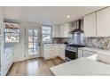 Bright kitchen featuring white cabinets, stainless steel appliances and a stylish backsplash at 2572 Chase St, Edgewater, CO 80214