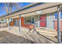 Inviting covered entrance featuring brick accents, a red front door, and a convenient carport at 5442 S Cedar St, Littleton, CO 80120