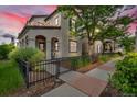 View of the side yard that has a walkway with greenery and a wrought iron fence and sitting area at sunset at 3372 Central Park Blvd, Denver, CO 80238