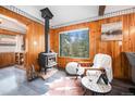 Cozy living room featuring a wood-burning stove, comfortable seating, and a view of the surrounding woods at 5672 Santa Clara Rd, Indian Hills, CO 80454