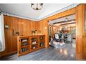Living room with wood paneling, hardwood floors, and stylish decor, leading into an open kitchen space at 5672 Santa Clara Rd, Indian Hills, CO 80454
