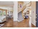 Elegant foyer with a curved staircase, hardwood floors, and a view into the dining room at 7141 Red Mesa Dr, Littleton, CO 80125