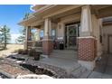 Inviting front porch with brick accents, decorative wreath, and meticulously landscaped garden beds at 12119 S Wanderlust Way, Parker, CO 80138