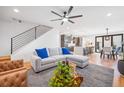 Inviting living room with modern staircase, gray sectional sofa with blue pillows, flowing into dining area and kitchen at 3928 Vrain St, Denver, CO 80212