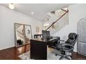 Office space with wood floors, a large desk, and view of staircase at 22336 E Bellewood Dr, Aurora, CO 80015