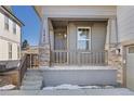 Inviting front porch with stone accents, gray siding, and concrete steps leading to the entryway at 17412 W 93Rd Pl, Arvada, CO 80007