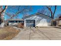 Home's exterior highlighting the blue paint, garage, brickwork, and expansive driveway at 2230 Miller Ct, Lakewood, CO 80215