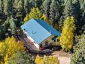 Aerial view of the house showcasing its deck, nestled among vibrant trees in a serene forest setting at 2785 Magpie Ln, Larkspur, CO 80118