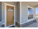 Inviting covered porch with a wood door framed by stone accents and a nearby window at 423 Basin Daisy St, Castle Rock, CO 80104