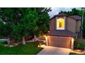 Inviting two-story home with lush green lawn and mature trees, accented by warm exterior lighting at 5150 Morning Glory Pl, Highlands Ranch, CO 80130