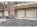 Attached garages with white doors and air conditioning units next to the asphalt driveway at 3872 S Dallas St # 7-304, Aurora, CO 80014
