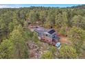 Aerial view of a two-story home with solar panels, a deck, and a hot tub surrounded by tall trees at 4574 Picutis Rd, Indian Hills, CO 80454