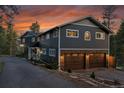 Charming home exterior with two-car garage, stone accents, and beautiful sunset at 4574 Picutis Rd, Indian Hills, CO 80454