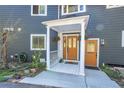 Inviting front porch with white pillars, wood-trimmed door and a view of the lush landscape at 4574 Picutis Rd, Indian Hills, CO 80454