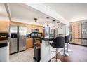 Modern kitchen with stainless steel appliances, wood cabinets, and breakfast bar with city view at 1625 Larimer St # 2601, Denver, CO 80202