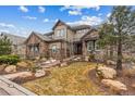 Charming home with stone and siding exterior, showcasing a landscaped front yard and inviting entrance at 4937 Hogback Ridge Rd, Morrison, CO 80465