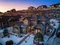 Beautiful home exterior at dusk with stone accents, a charming entryway, and snow-covered landscaping at 4937 Hogback Ridge Rd, Morrison, CO 80465